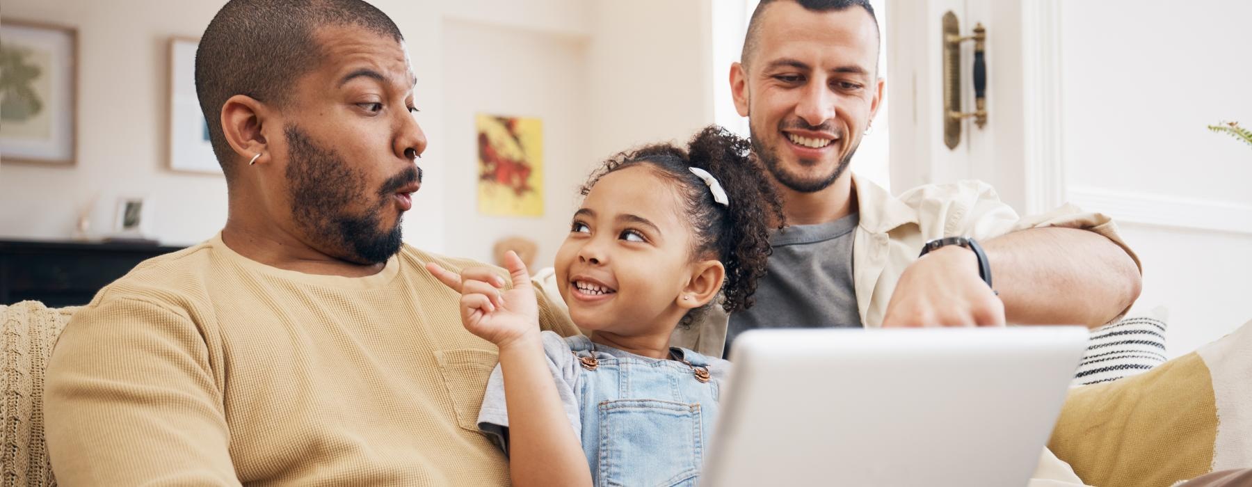 two men and a little girl sitting on a couch